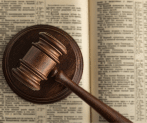 Wooden judge’s gavel resting on open law book.