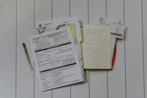Stack of documents with pens and folders on a white table.