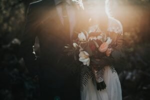 Person holding flowers in a dimly lit ceremonial setting.