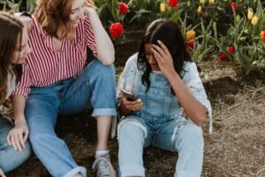 Mom and daughter sitting by a flower bed having a conversation.